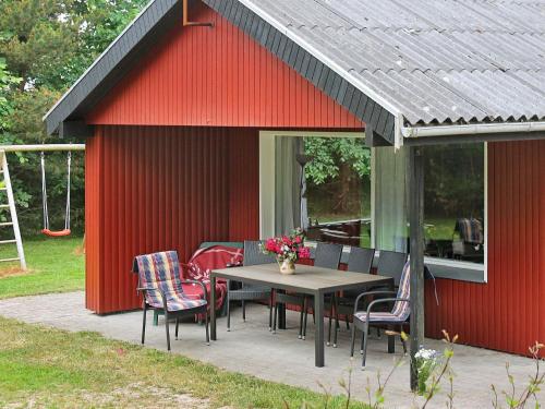 ロモ・キルケビーにある6 person holiday home in R mの赤い小屋にテーブルと椅子が備わるパティオ