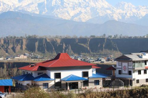 a building with a red roof with mountains in the background at Sunshine Resort Pokhara - Your Private Paradise in Pokhara