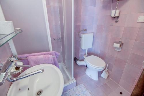 a pink bathroom with a toilet and a sink at Bastinac 1 in Veli Lošinj