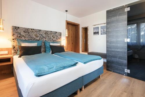 a bedroom with a large bed with blue sheets at Hotel VIKTORIAS HOME Kufstein in Kufstein