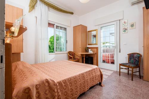 ein Schlafzimmer mit Bett, Schreibtisch und Fenster in der Unterkunft Hotel Marco Polo in Lignano Sabbiadoro