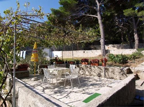 een patio met een tafel en stoelen en een parasol bij Bastinac 2 in Veli Lošinj