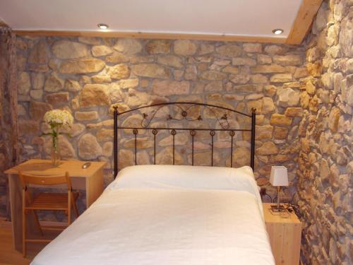 1 dormitorio con cama y pared de piedra en Casa Rural Ortulane, en Urduliz