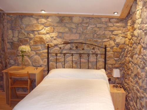 Un dormitorio con una cama y una pared de piedra. en Casa Rural Ortulane, en Urduliz