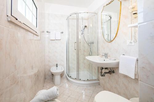 ein Badezimmer mit Dusche, Waschbecken und Toilette in der Unterkunft Hotel Marco Polo in Lignano Sabbiadoro