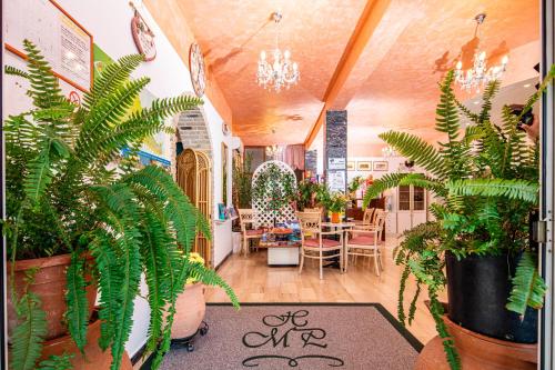 リニャーノ・サッビアドーロにあるHotel Marco Poloのたくさんの植物とテーブルが並ぶ部屋