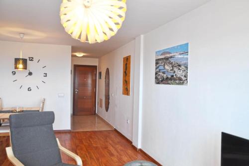 a living room with a clock on the wall and a chair at Casa Lucía in Vecindario