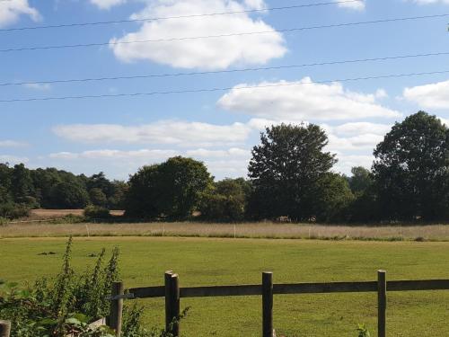 a fence in front of a green field at The Nest at Bramble Cottage Lacock in Lacock