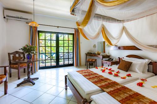 a bedroom with two beds and a desk and a window at Diani Sea Resort - All Inclusive in Diani Beach
