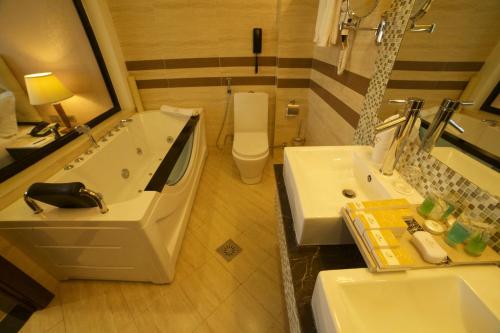 a bathroom with a tub and a toilet and a sink at Getfam Hotel in Addis Ababa