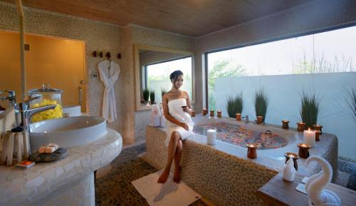 a woman sitting on a tub in a bathroom at Barahi Jungle Lodge in Meghauli