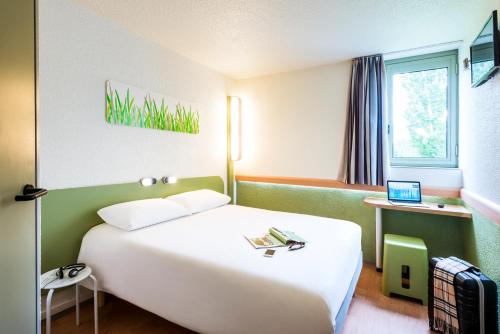 Cette chambre comprend un grand lit blanc et un ordinateur portable. dans l'établissement ibis budget Caen Hérouville, à Hérouville-Saint-Clair