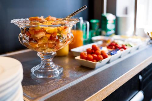 a glass bowl filled with fruit on a counter at mk hotel münchen max-weber-platz in Munich