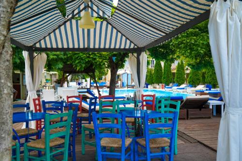 a group of chairs and tables under a blue and white umbrella at Krikonis Hotel in Ioannina