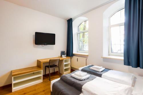 ミュンヘンにあるmk hotel münchen max-weber-platzのデスク、テレビが備わる客室で、ベッド2台を利用できます。