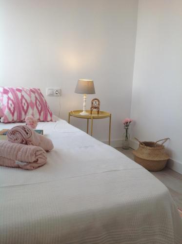 um quarto com uma cama branca com lençóis cor-de-rosa e um candeeiro em PINK LEMON apartments em Córdoba