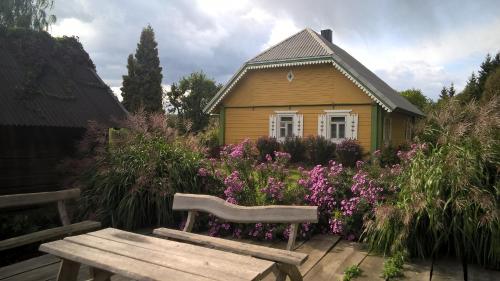 a bench in front of a small house with flowers at Kačiūniškis in Kaciūniškiai