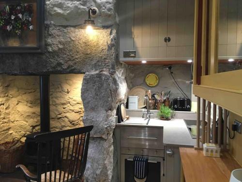 a kitchen with a stone wall and a sink at 1 Bryn Tirion Uchaf in Pwllheli