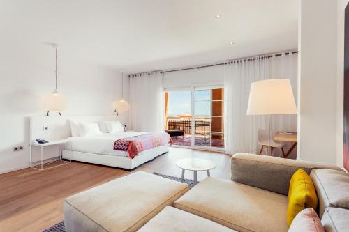 a white bedroom with a bed and a couch at Ama Islantilla Resort in Islantilla