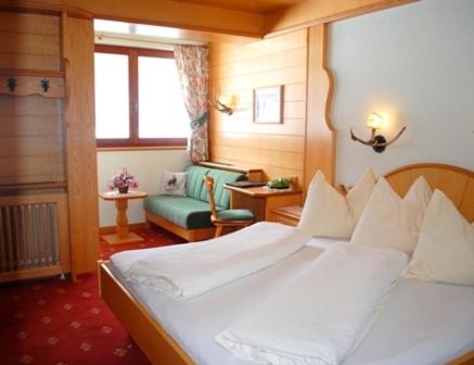 a bedroom with a large white bed and a chair at Hotel Jagdhof in Ramsau am Dachstein