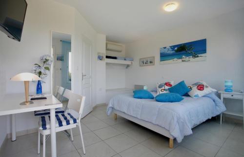 a bedroom with a bed with blue pillows and a desk at Logis Hôtel Corintel Bordeaux Est in Tresses