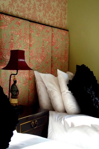 a bed with white pillows and a lamp on a table at Beachlands Hotel in Weston-super-Mare