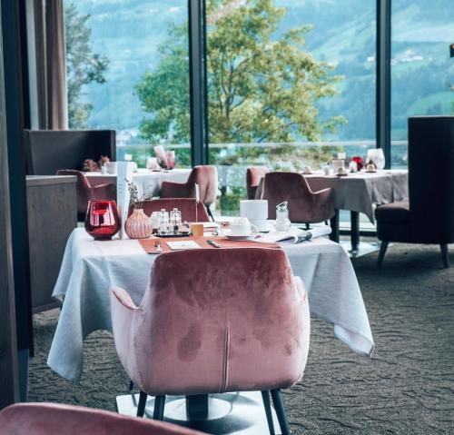 un comedor con mesas y sillas y una gran ventana en Sport- und Wellnesshotel Held 4 Sterne Superior, en Fügen