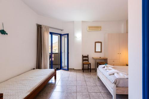 a room with two beds and a table and a desk at Voukelari Rooms in Plakias