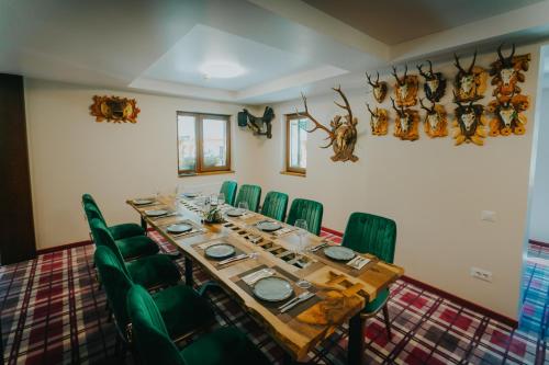 a dining room with a long table and green chairs at Lostrita - Pastravarie, Hotel & SPA in Baia Mare