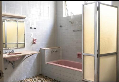 uma casa de banho com uma banheira rosa e um lavatório. em Hostel Senhor do Café em Botucatu