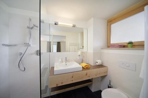 a white bathroom with a sink and a shower at Vitalhotel Rainer in Ultimo