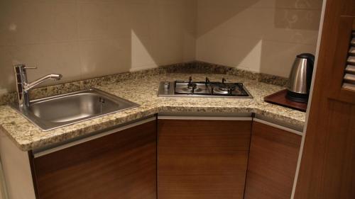 a kitchen with a sink and a counter top at Big Ben Hotel Suites in Amman