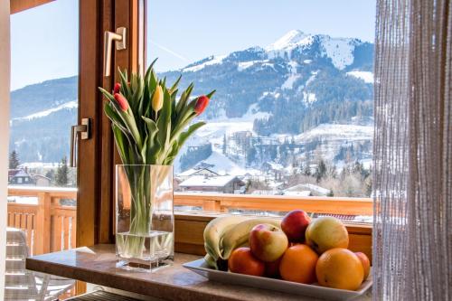 a table with a plate of fruit and a vase of flowers at Appartements Monuth in Bad Hofgastein