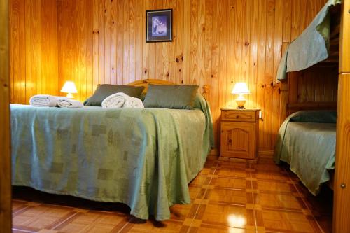 1 dormitorio con 2 camas y pared de madera en Apart Flavia en Carhué