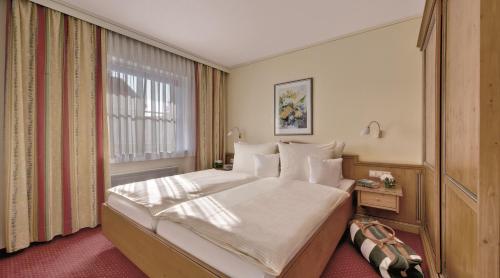 ein Schlafzimmer mit einem großen Bett und einem Fenster in der Unterkunft Hotel Birnbacher Hof in Bad Birnbach