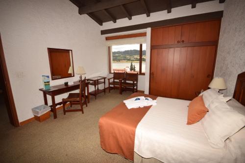 a hotel room with a bed and a desk and a table at D'Acosta Hotel Sochagota in Paipa