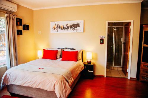 a bedroom with a large bed with red pillows at Maroela Guest Lodge in Thabazimbi