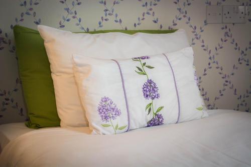 a bed with three pillows with purple flowers on it at Beachlands Hotel in Weston-super-Mare