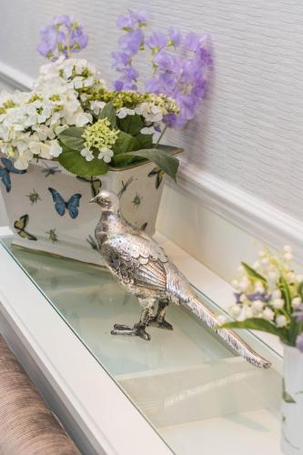 a bird sitting on a table next to a vase of flowers at Beachlands Hotel in Weston-super-Mare