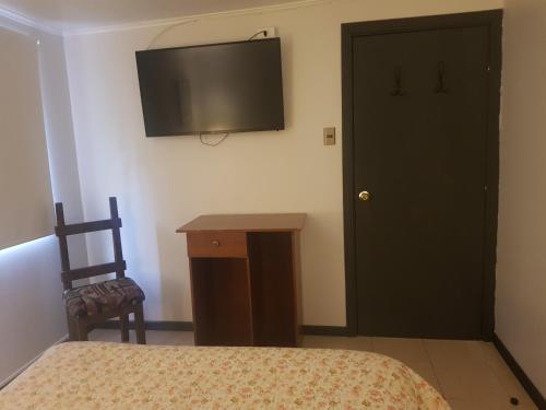 a bedroom with a bed and a television on the wall at Hostal Centro Montt in Temuco