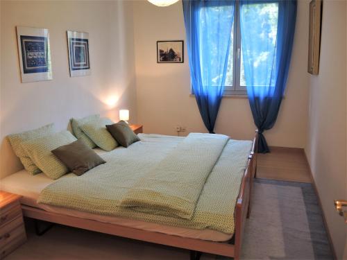 1 dormitorio con 1 cama con cortinas azules y ventana en Verena, en Ascona