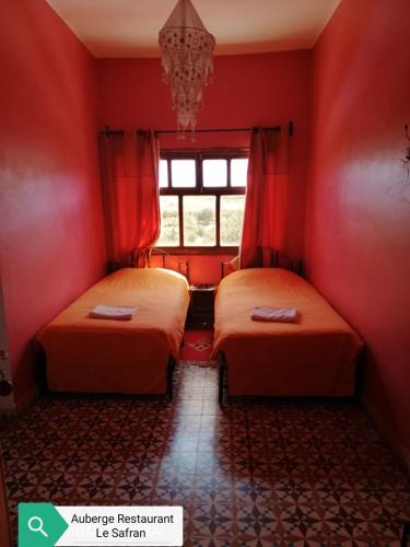 two beds in a room with red walls and a window at Auberge Restaurant le Safran in Taliouine