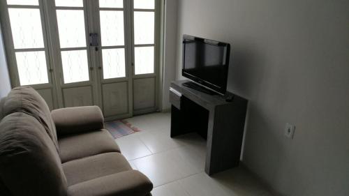 a living room with a television and a chair at Casa para famílias, próximo a Basílica de Nossa Senhora Aparecida in Aparecida