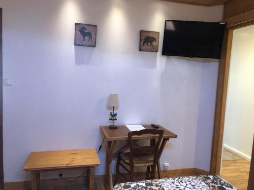 a room with a table and a television on a wall at AU COEUR DES ALPES in Marignier