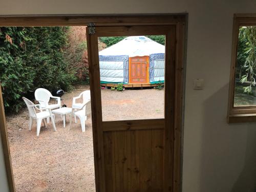 a door leading to a yurt with a table and chairs at yourte Coeur de Combray in Ernes