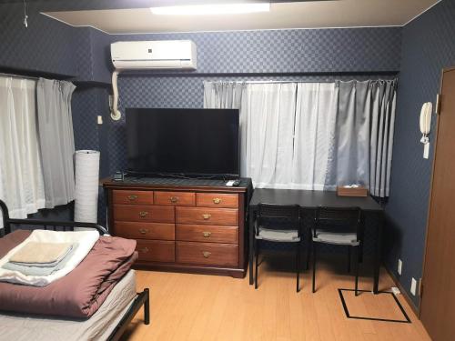 a living room with a television and a dresser with a couch at K2 Fuchu ケイツー府中 in Fuchu