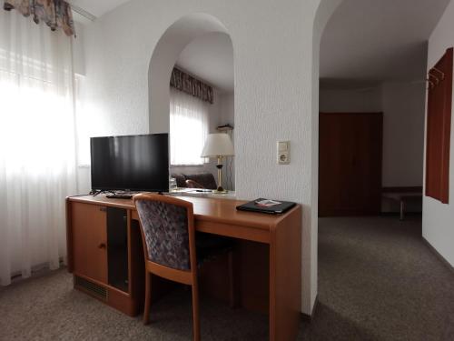 a desk with a television and a chair in a room at Hotel Römerhof in Straubing