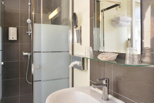La salle de bains est pourvue d'un lavabo et d'une douche avec un miroir. dans l'établissement Logis Hôtel Restaurant Le Puits Doré, à Richelieu