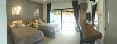a bedroom with two beds and a sliding glass door at Suwi Coco Ville Resort in Ubon Ratchathani