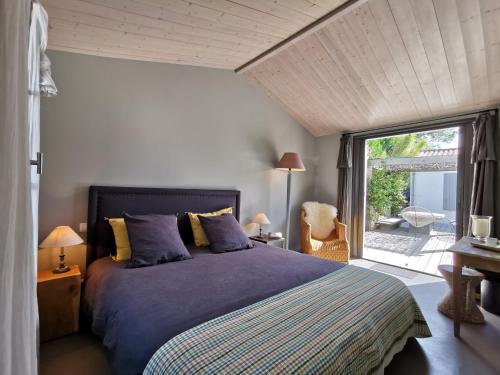 a bedroom with a bed and a large window at Derrière la plage : suite, patio et pergola in Le Bois-Plage-en-Ré